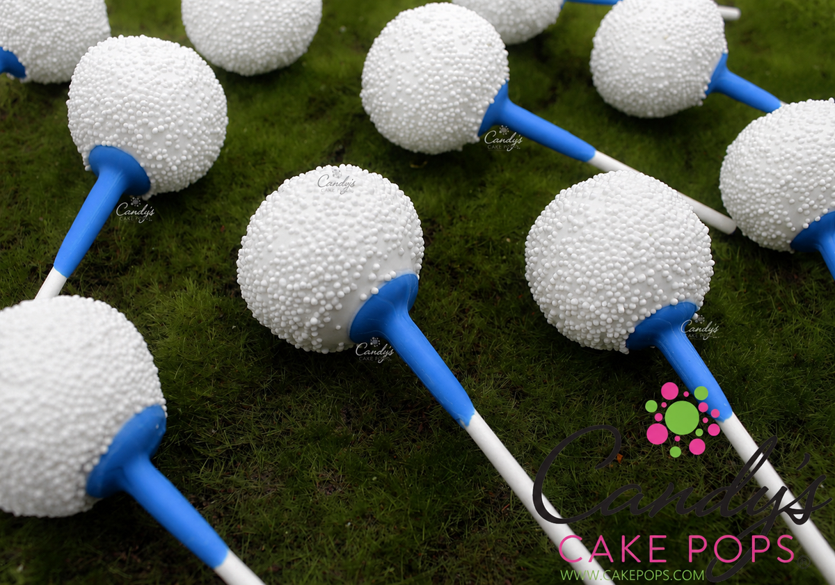 Golf Ball Cake Pops with blue golf tees arranged on a green moss-like surface. A Candy's Cake Pops watermark is visible.